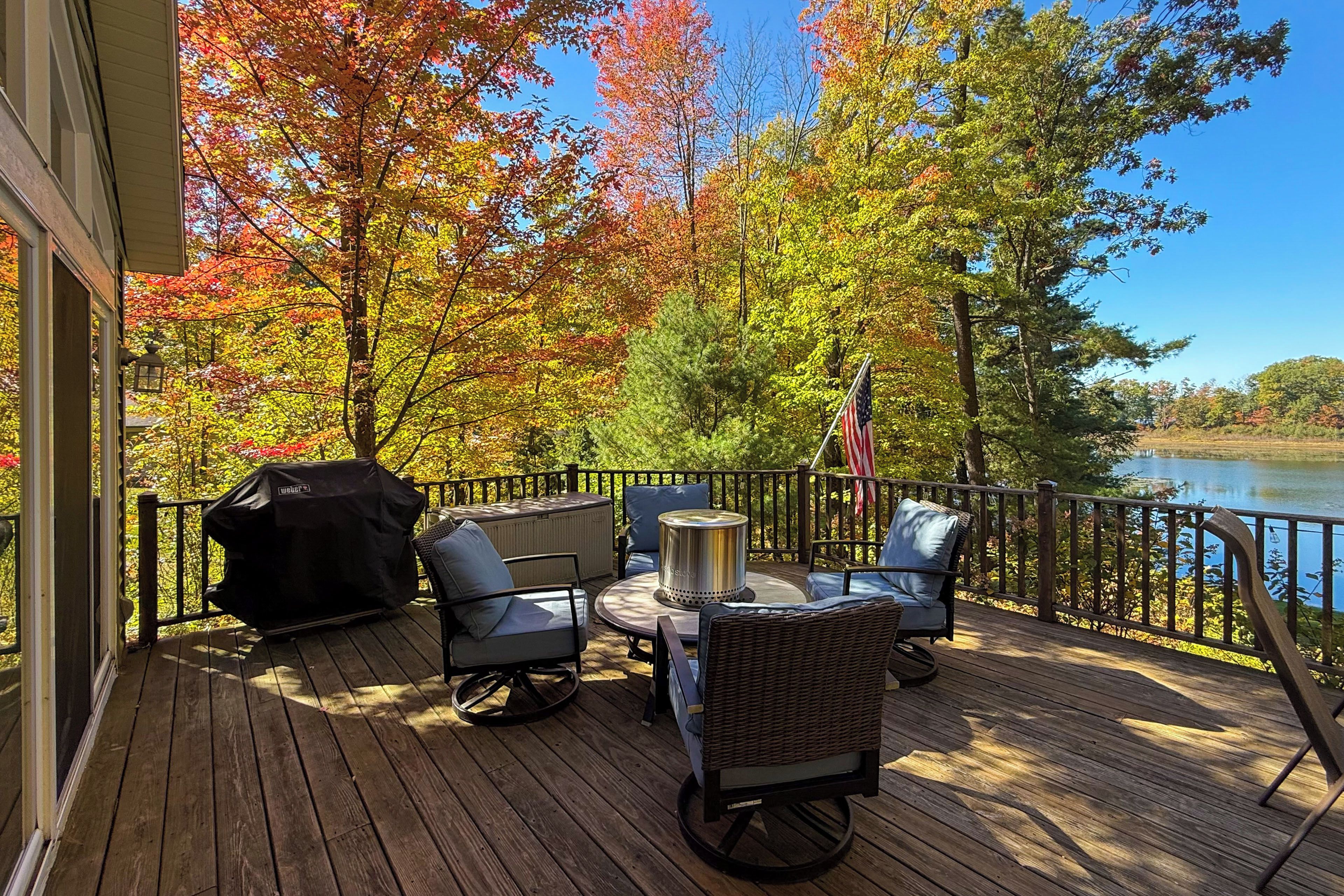 Une terrasse dotée de mobilier d’extérieur, d’un barbecue et offrant une vue sur un lac.