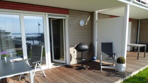 Une terrasse avec une table et des chaises, un barbecue et une plante en pot.