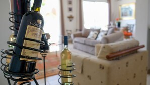 Una sala de estar con sofá y una estantería para vinos con botellas.