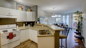 A modern kitchen with white cabinets, a built-in stove, and a large island with a sink. - Garden level getaway at Discovery Bay (Kelowna)