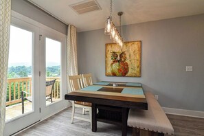 Ein Essbereich mit Tisch und Stühlen, einer Bank, einem Gemälde einer Eule und Blick durch eine Glastür nach draußen.