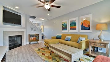 A modern living room with a fireplace, a sofa, a coffee table, and artwork on the walls.