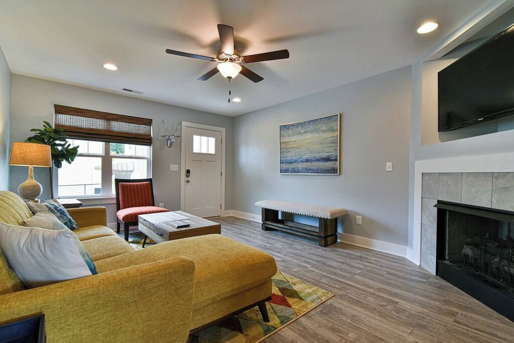 A living room with a sofa, a coffee table, a fireplace, and a ceiling fan.