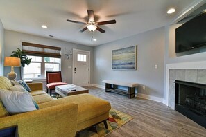 Ein Wohnzimmer mit einer Couch, einem Couchtisch, einem Kamin und einem Deckenventilator.