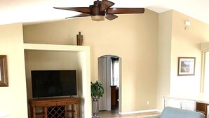 A living room with a flat-screen TV, a ceiling fan, a coffee table, and two sofas. - Screened Heated Pool, Boat Ramp Nearby, Beaches (Port St Lucie)