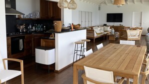 A spacious kitchen with modern appliances, a dining area with wooden furniture, and a large island. - Villa Sunset | Ocean View - Located in  Fabulous Pointe Milou with Private Pool (Pointe Milou)