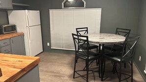 Eine kompakte Küche mit einem weißen Kühlschrank, einer Mikrowelle und einem Essbereich mit einem runden Tisch und vier Stühlen.