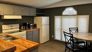 Eine kompakte Küche mit Herd, Mikrowelle und Kühlschrank, einer Holz Arbeitsplatte sowie einem Essbereich mit Tisch und Stühlen.