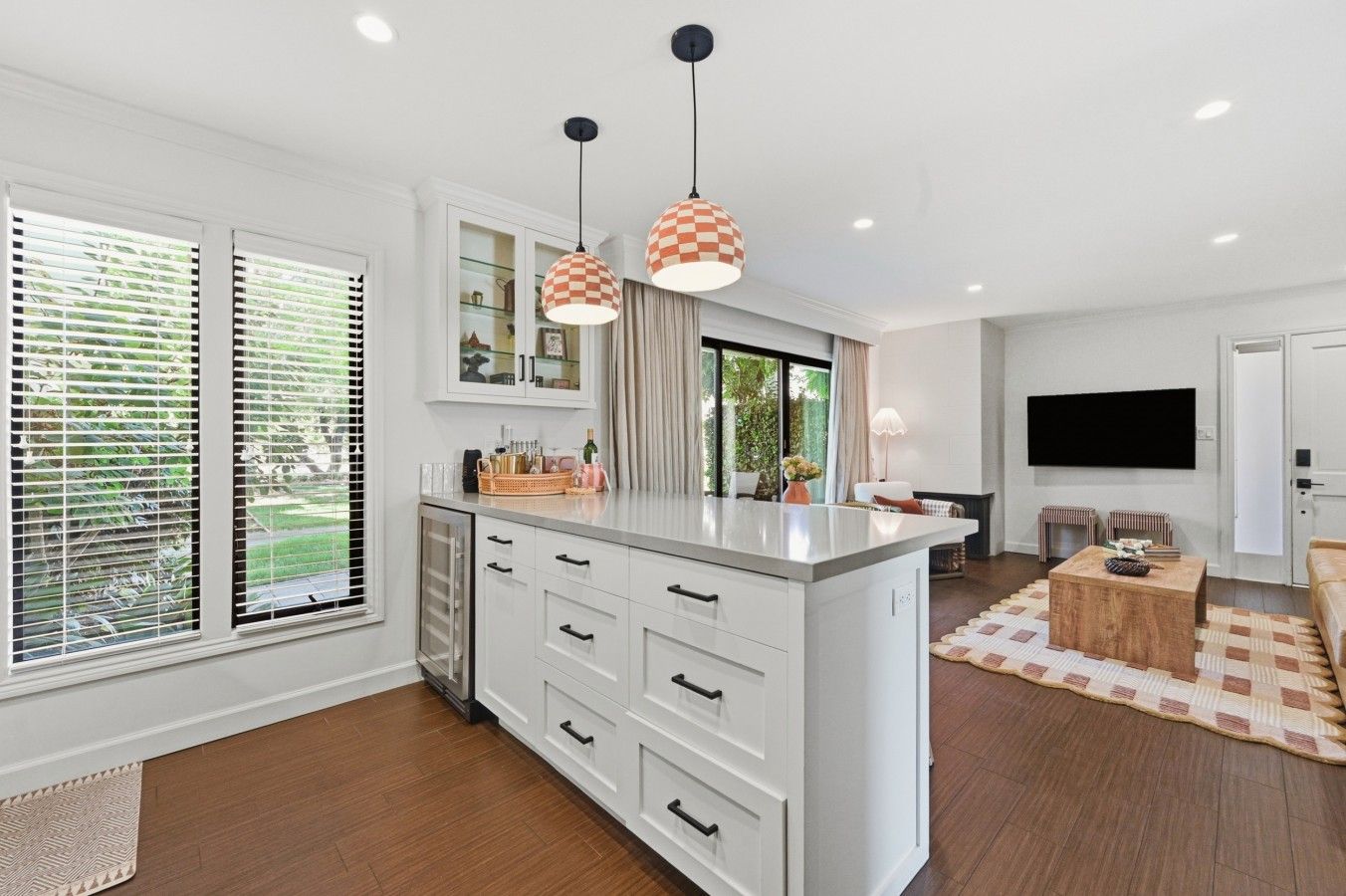 A modern kitchen with a central island, white cabinetry, and pendant lighting.