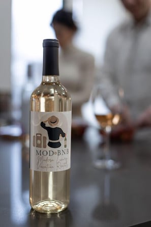 A bottle of MOD BNB wine on a bar counter with a blurred background of a person.