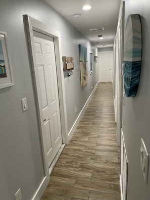 A hallway with wooden flooring, white walls, and a door at the end.