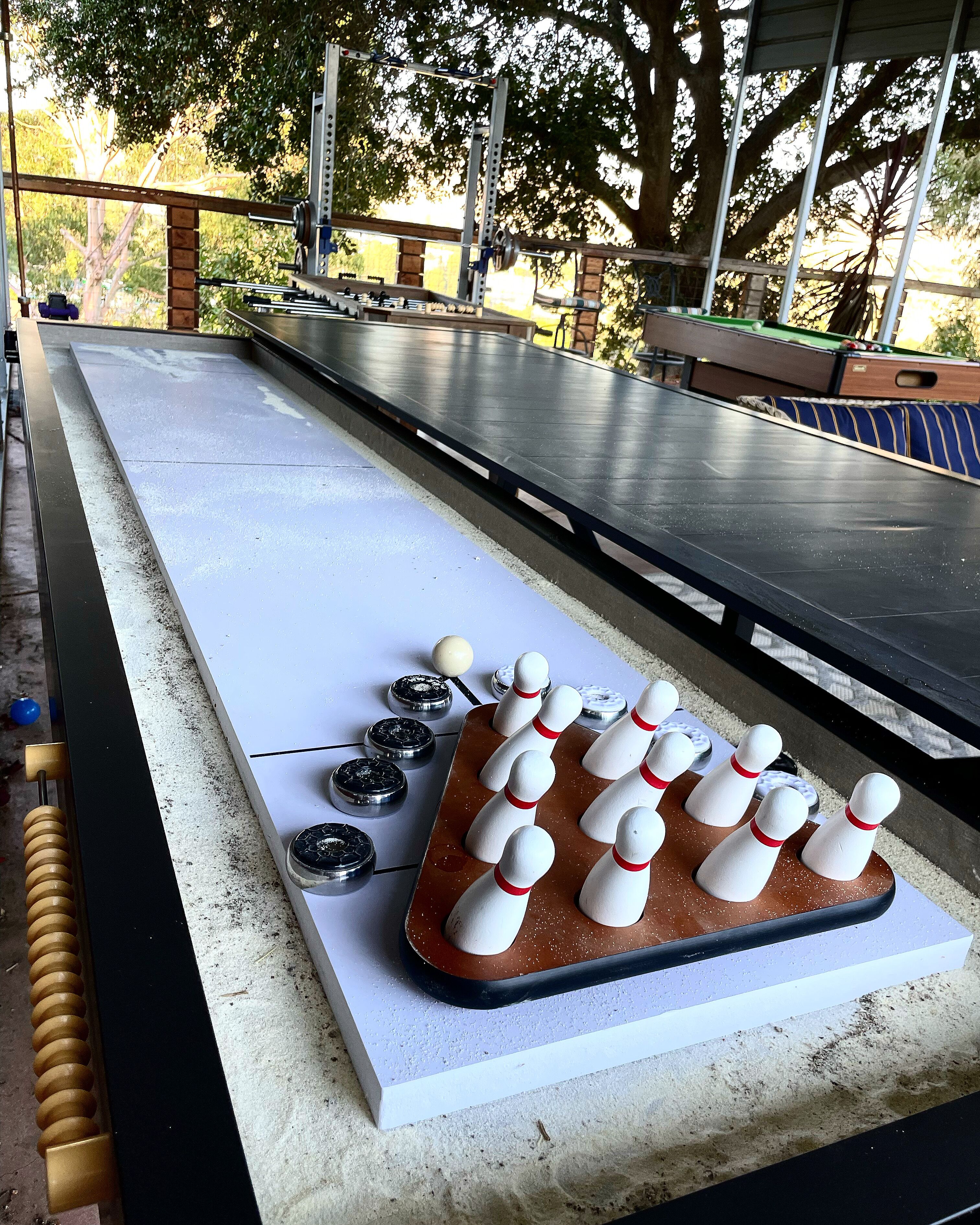 A bowling alley with a bowling lane, pins, and a ball rack.