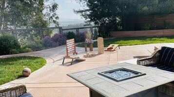 An outdoor patio with a fire pit, seating area, and a children's play area.