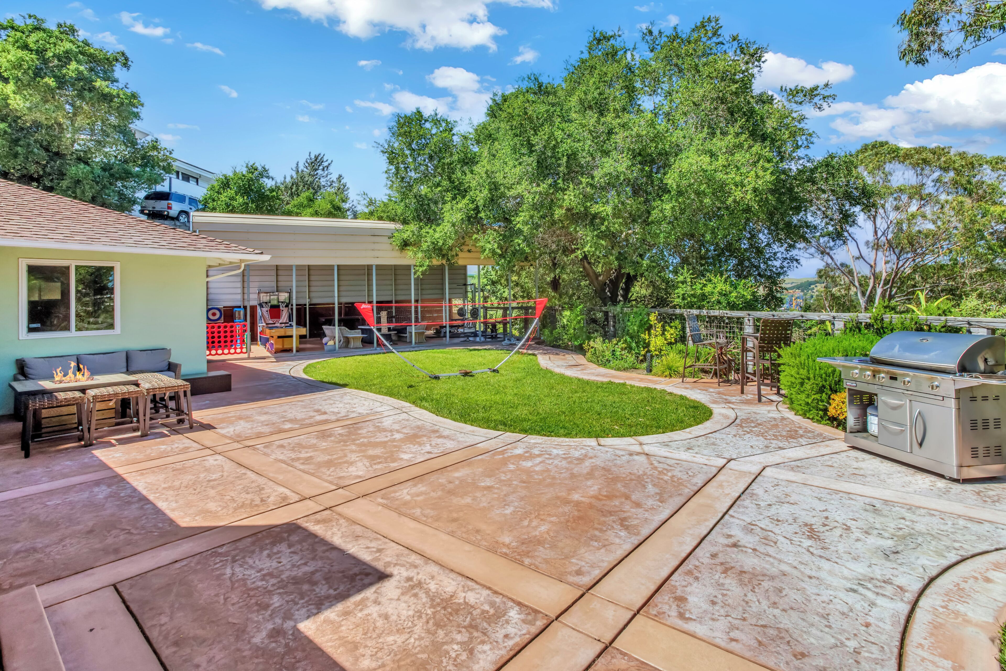 Ein Garten mit Terrasse, Grill und Schaukel.