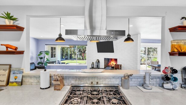Een moderne keuken met een gasfornuis, hanglampen en uitzicht op het buiten.
