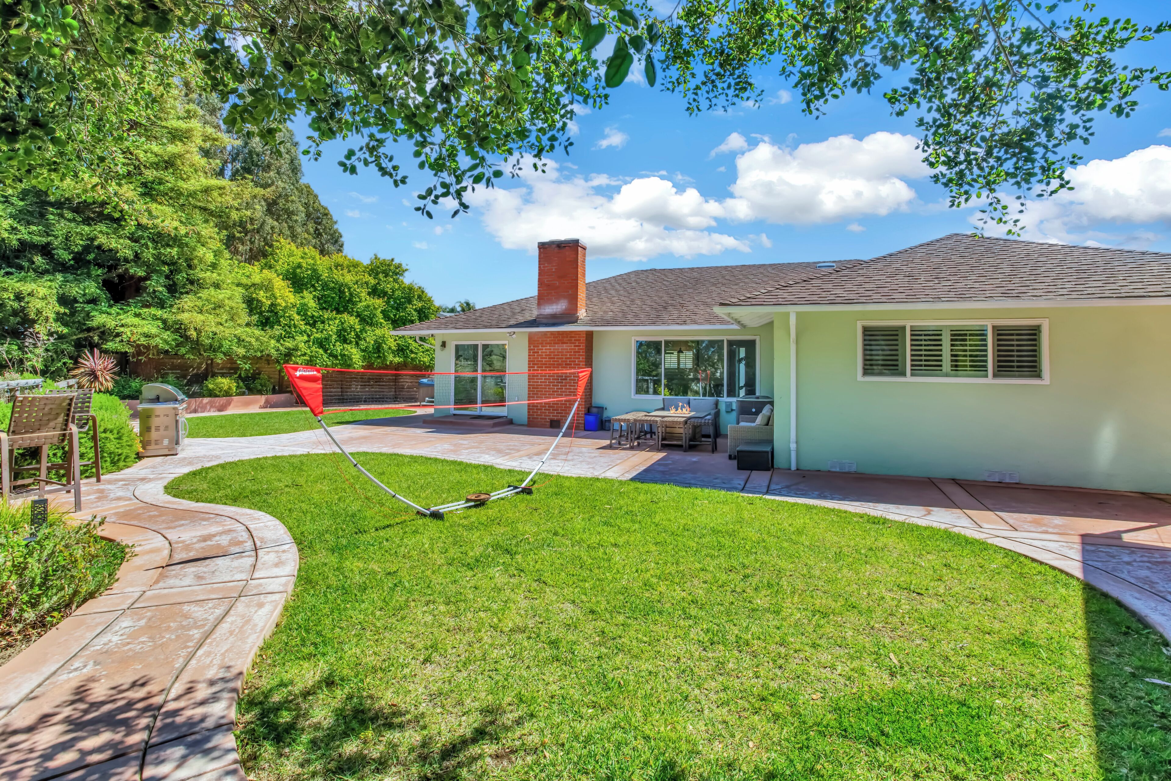 A house with a patio, a lawn, and a red object in the yard.