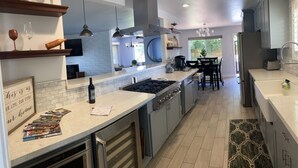 Een moderne keuken met een centraal eiland, roestvrijstalen apparatuur en een eethoek met een tafel en stoelen.