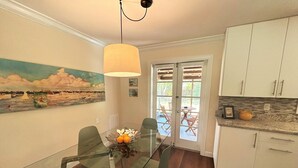 Una cucina moderna con mobili bianchi, un tavolo da pranzo in vetro e un quadro appeso alla parete.