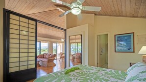 A spacious bedroom with a large bed, a ceiling fan, and a view of the outdoor patio area. - Full 🌊 Views & 🌋Views Watch the🌅 and 🌕 rise (Koloa)