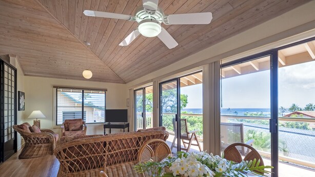A spacious living room with a large sofa, a television, and a balcony with a view of the ocean. - Full 🌊 Views & 🌋Views Watch the🌅 and 🌕 rise (Koloa)