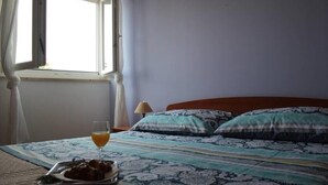 Una cama con ropa de cama estampada, una mesita de noche con lámpara, y una bandeja con comida y bebida.