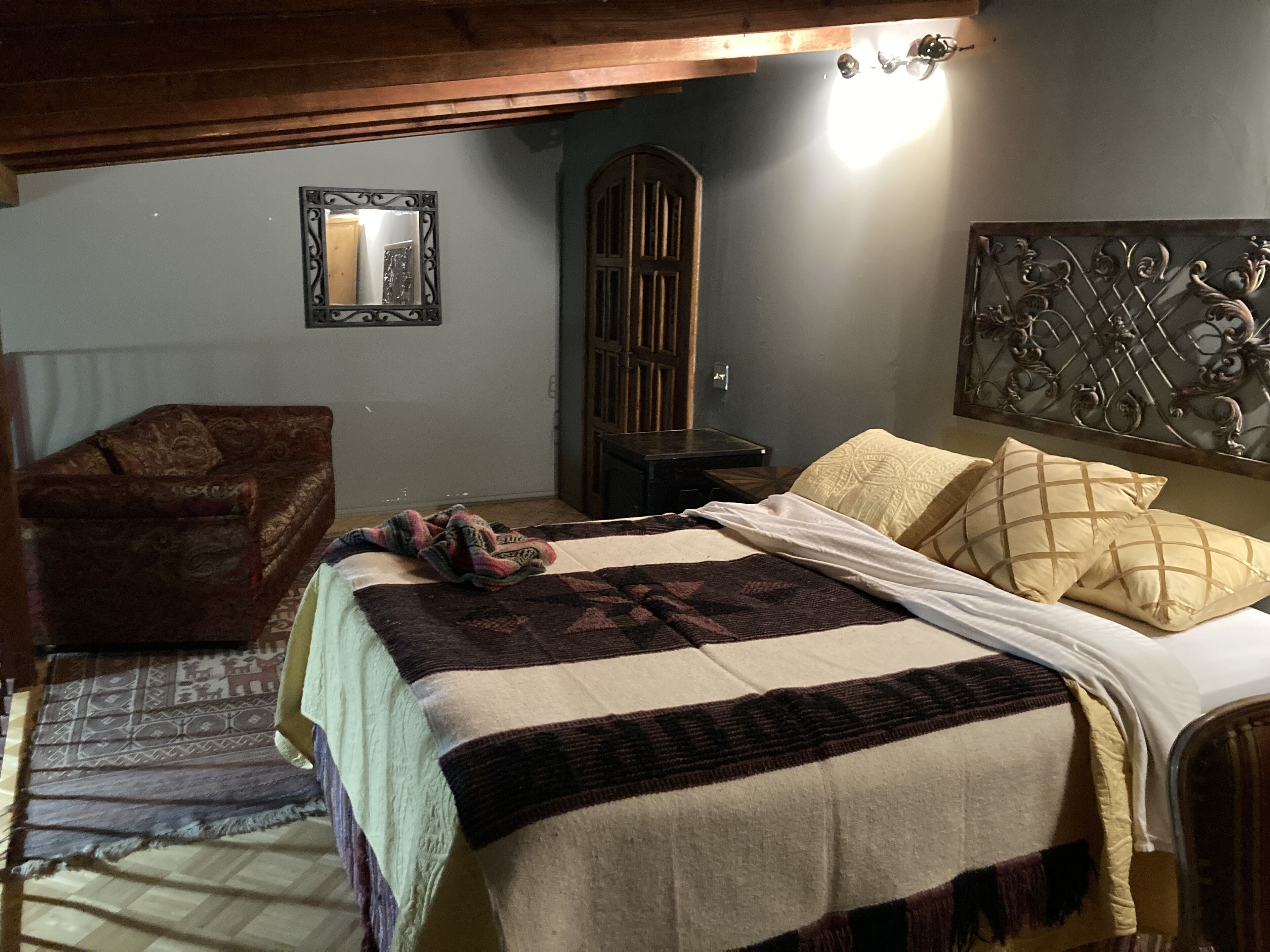 Ein gemütliches Schlafzimmer mit einem Bett, einem Holzstuhl, einem Kleiderschrank und einem dekorativen Kopfteil.