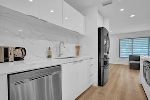 Enjoy cooking in this well-lit kitchen with sleek cabinetry, a dishwasher, and a large refrigerator.