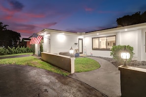 Stunning home with a well-manicured lawn and a driveway leading to a gated entrance.