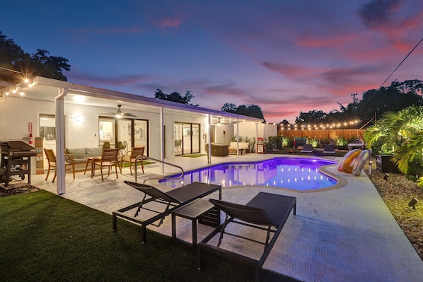 Relax by the pool surrounded by a covered patio and lush greenery.