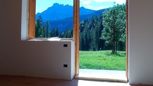 Een kamer met een groot raam met uitzicht op een bergachtig landschap.