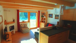 Een gezellig blokhutinterieur met houten inrichting, een open haard, een eethoek en uitzicht op de natuur.