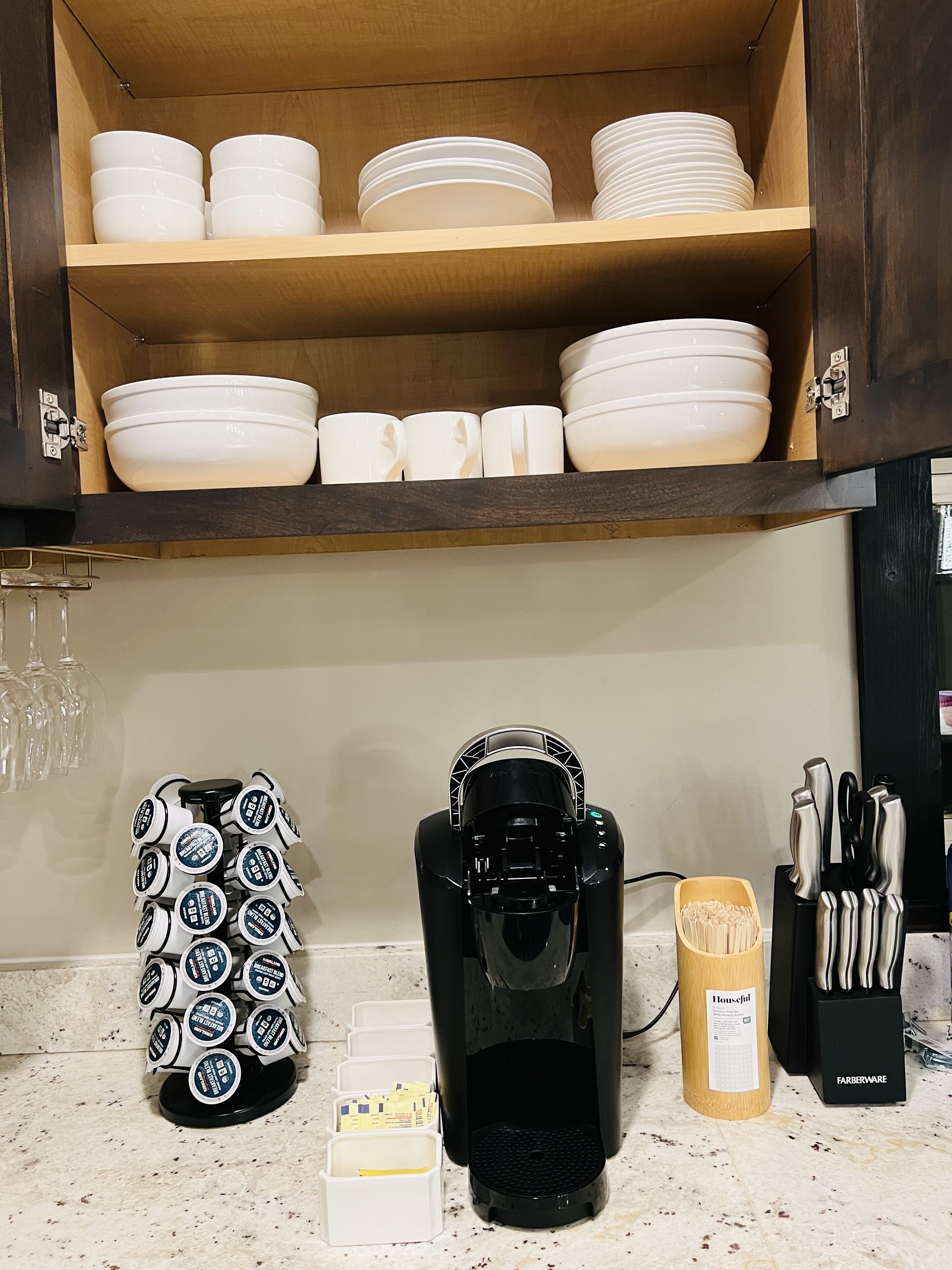 Una cocina con cafetera, tazas y utensilios en la encimera.
