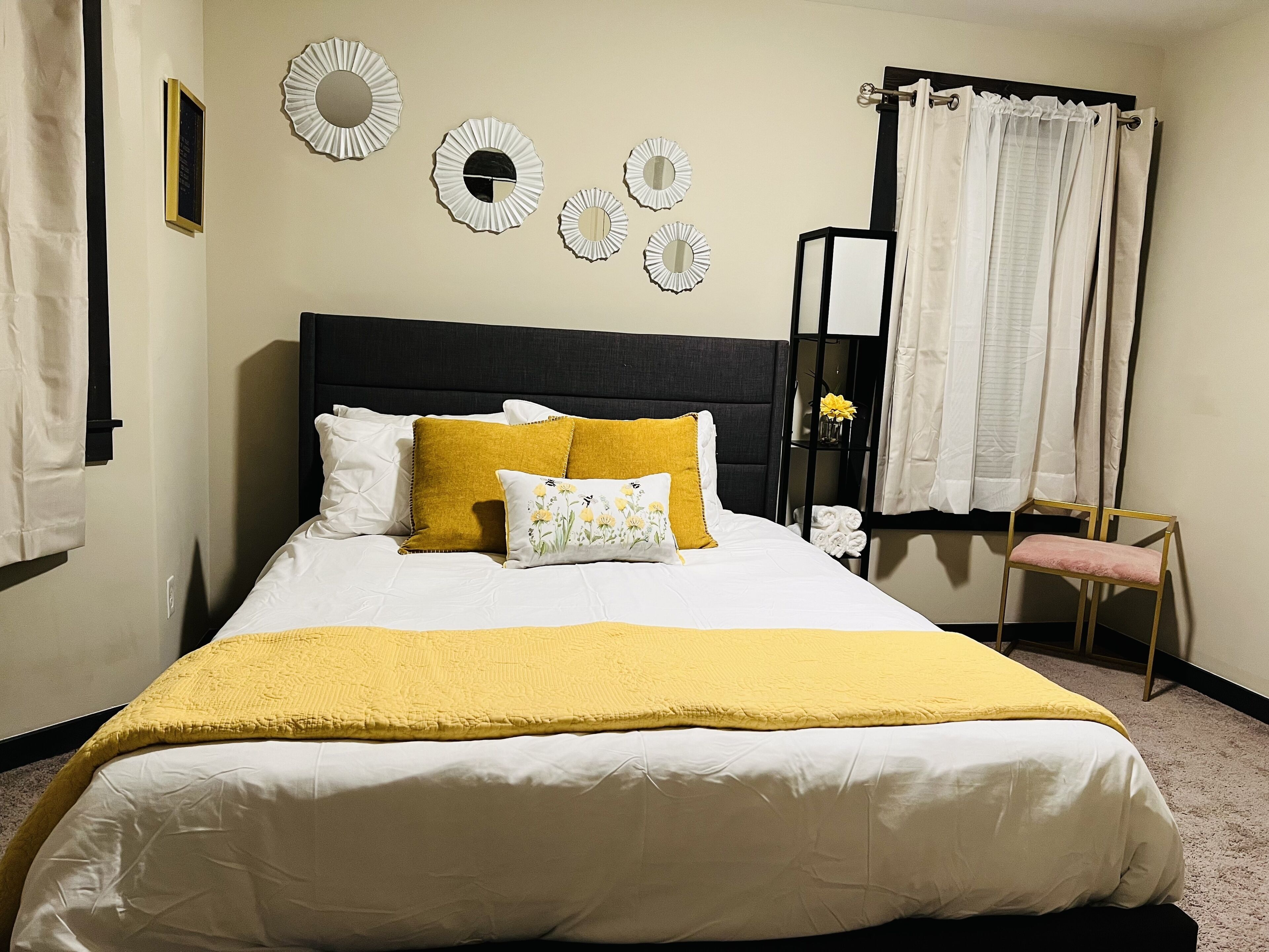 A neatly made bed with a yellow throw blanket, white pillows, and a mustard-colored pillow.