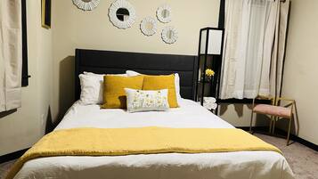 A neatly made bed with a yellow throw blanket, white pillows, and a mustard-colored pillow.