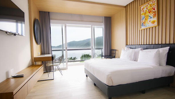 Camera d'albergo moderna con un ampio letto, una scrivania e vista sul mare.