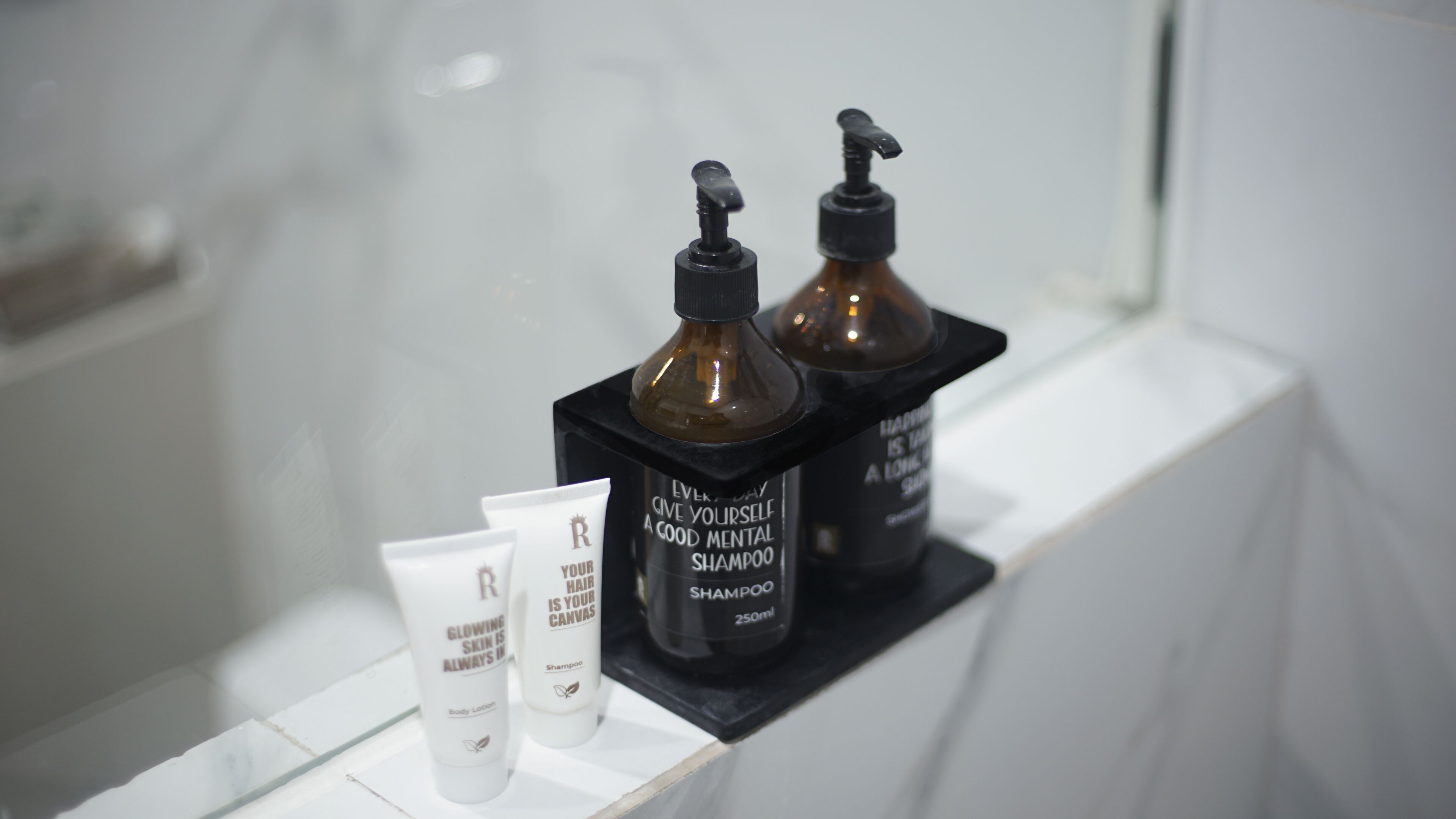 Un estante de baño con dos botellas de champú color café y dos tubos de loción corporal blanca.