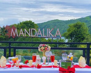 A table set for a meal with a view of a mountainous landscape and a sign reading "MANDALIKA".