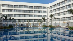 Un hotel a più piani con area piscina centrale, circondata da balconi e condizionatori.