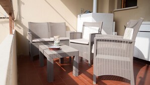 Eine Terrasse mit Korbmöbeln, darunter ein Tisch und zwei Stühle, sowie ein kleiner Korb.