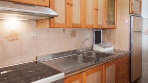 Eine Küche mit Holzschränken, einer Edelstahlspüle, einem Herd und einem Kühlschrank.