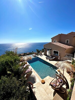 A pool area with a view of the sea, surrounded by greenery and furnished with lounge chairs and a swing chair. - Villa (Saint-Raphaël)