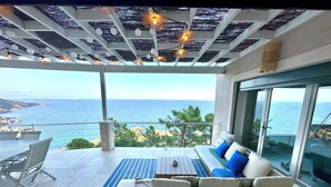 Ein Balkon mit einer Couch, einem Esstisch und Stühlen mit Blick auf die Küste.