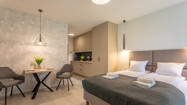 A modern hotel room with a large bed, a desk with two chairs, a TV, and a wall with a textured pattern. - Vacation apartment by the sea, vacation on the island of Usedom, Apartment Matejki 2 (Swinoujscie)