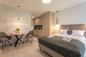 Una habitación de hotel moderna con una cama grande, un escritorio con dos sillas, un televisor y una pared con textura.