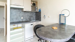 Ett kompakt kök med diskmaskin, mikrovågsugn och diskho. Där finns ett litet bord med ett bröd på.