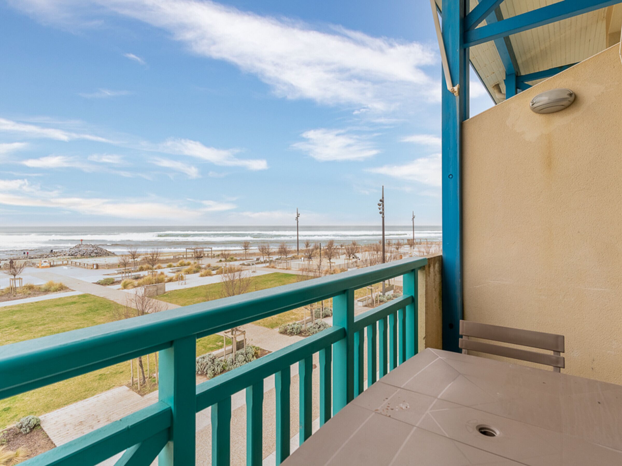A balcony with a view of the beach and ocean.