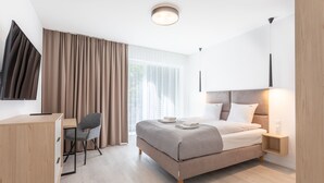 Une chambre d’hôtel moderne équipée d’un lit, d’un bureau, d’une chaise et d’un téléviseur.