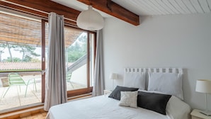 Een slaapkamer met een groot bed, een nachtkastje, een raam met gordijnen en uitzicht op de omgeving.