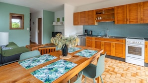 Een moderne keuken met houten kastjes, een fornuis en een eethoek met een tafel voor vier personen.
