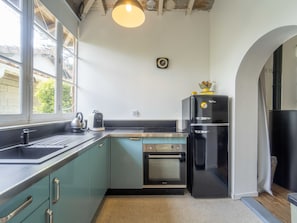 A kitchen with a window, a sink, a kettle, a toaster, a refrigerator, and an oven.
